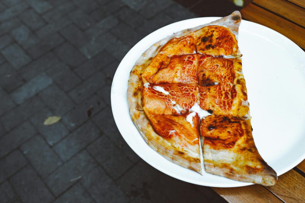 Delicious homemade calzone sliced on a white plate, perfect for an outdoor meal.